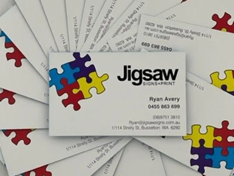 Jigsaw Signs + Print business cards fanned across a table
