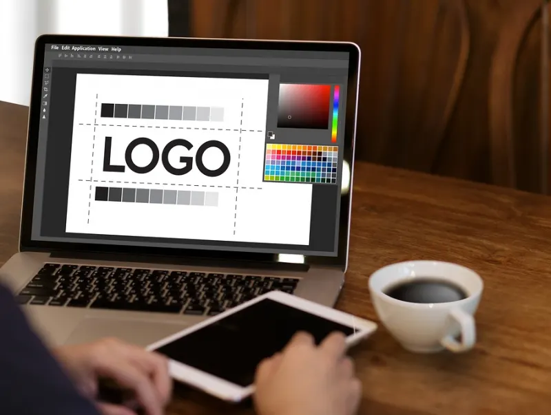 Logo design on a laptop beside a coffee cup