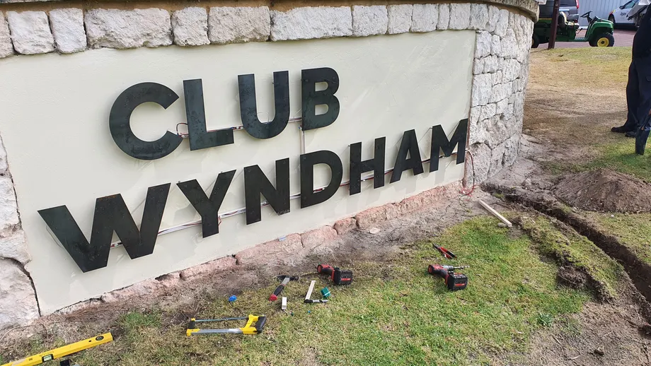 Club Wyndham letters being installed on the stone entry wall