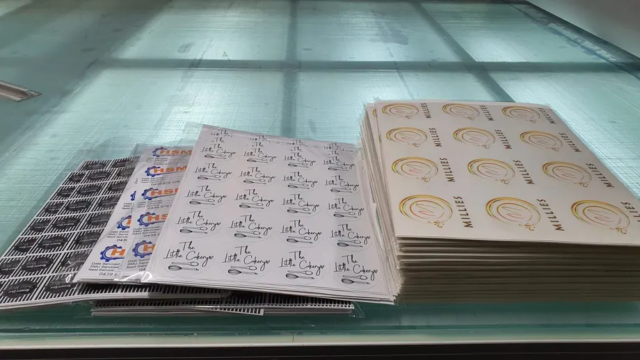 Sheets of printed stickers and labels stacked on the bench