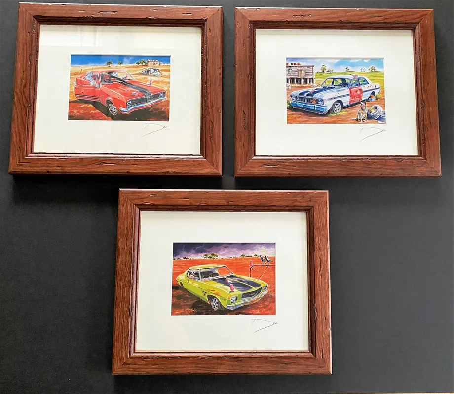 Three framed car paintings with white mats