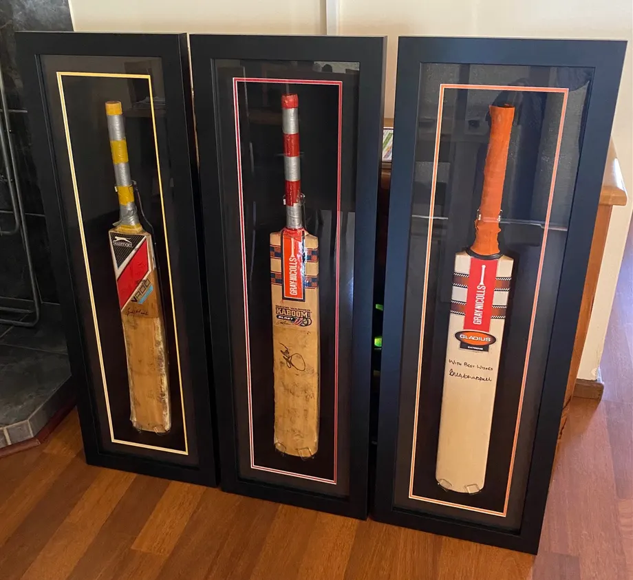 Three signed cricket bats in shadow box frames