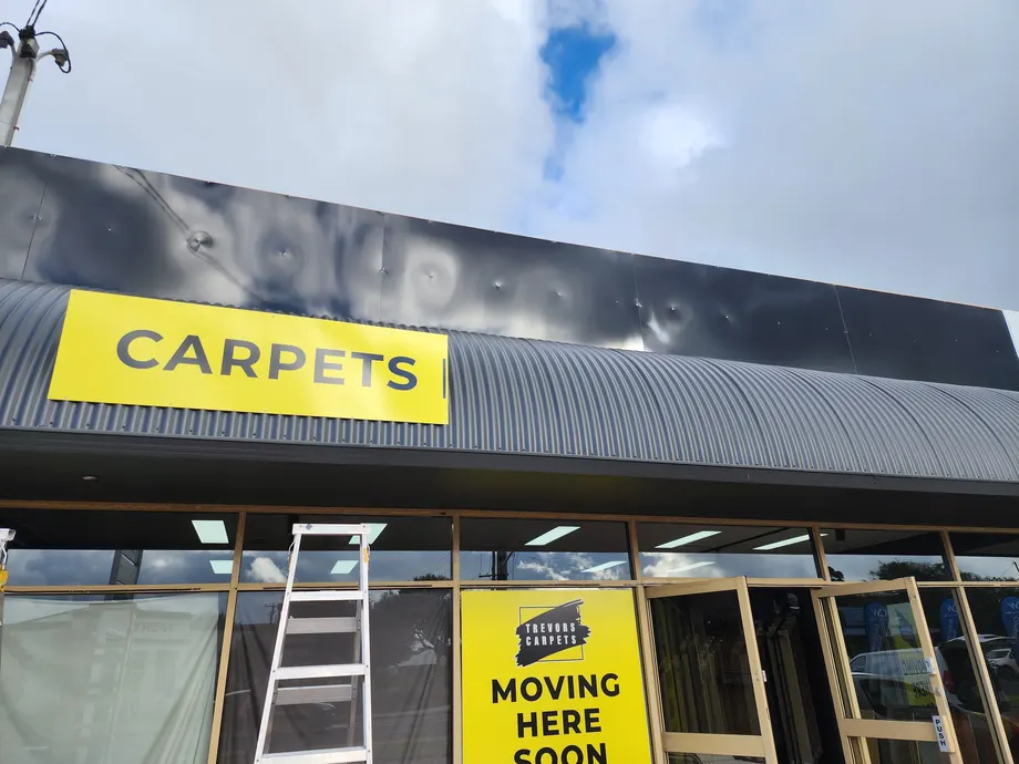 Trevors Carpets fascia panel going up above the shop windows