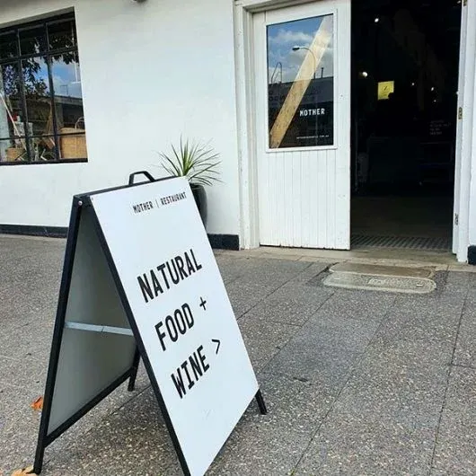 White A-frame sign pointing customers to natural food and wine
