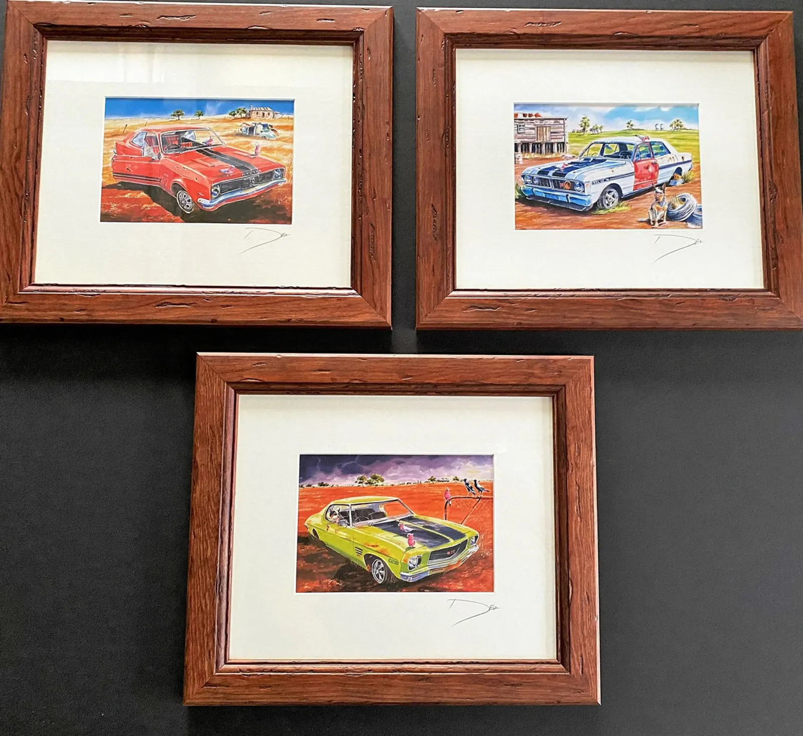 Three framed car paintings in timber frames